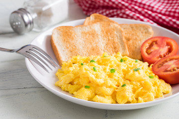 Scrambled egg served with toast and tomato .