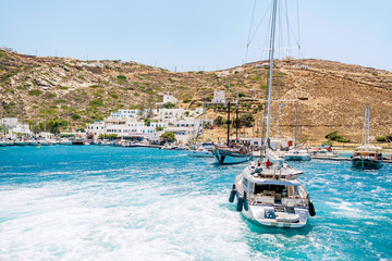 A yacht heads towards the port on the Greek island of Ios. Stunning turquoise waters of the Greek...