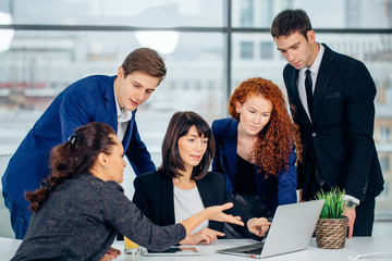 Fototapeta premium Group of happy diverse male and female business people in formal gathered around laptop computer in office