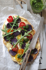 Flammkuchen mit blauen Kartoffeln, bunten Tomaten, Rucola und Rucolapesto