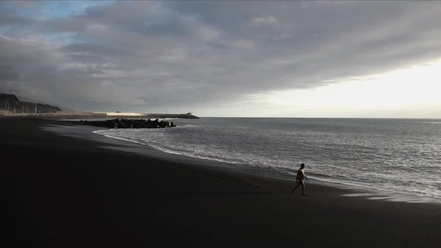 Canary Islands Jan 2018 - A man in swimwear walks along on a black volcanic sand beach in La Palma.