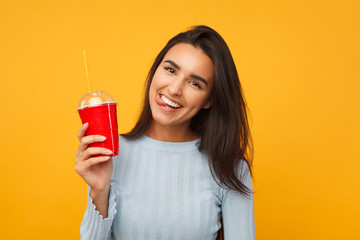 Brunette cheerful girl holding a soda cup