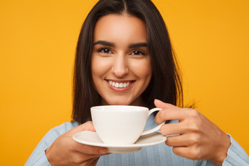 hispanic young woman smiling and holding a cup of coffee