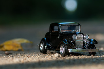 Fototapeta na wymiar Close-up on a vintage car on a road in a forest. Childhood memories. Shallow depth of field.
