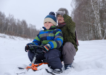two boys sitting on a sled in the woods on a walk