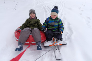 Fototapeta na wymiar two boys go snow sledding and tubing