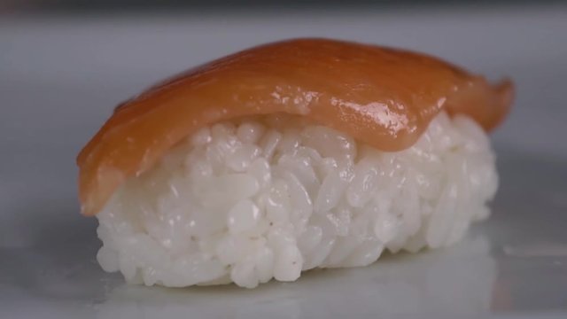 People puts slices of red fish to the surface. Close up.