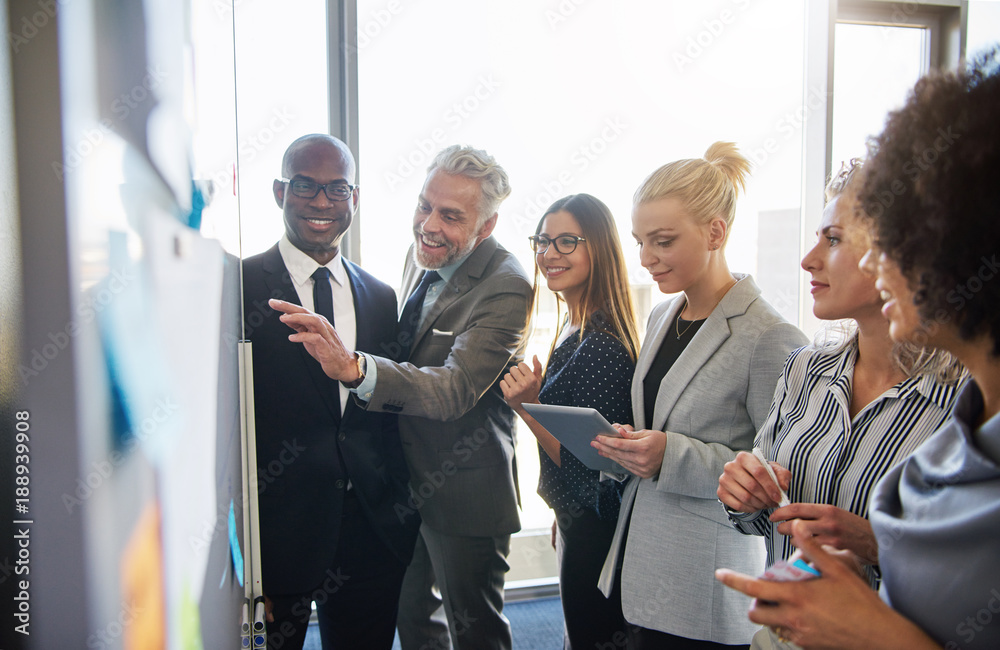 Wall mural smiling colleagues strategizing together on a whiteboard in an office