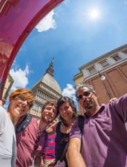 Four people selfie, vacation in italian cities. Torino, Mole Antonelliana, fish eye view, Turin, Italy. Backlight, sun star.