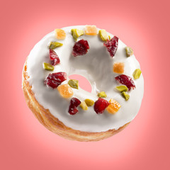 Cream coated donut with dried fruits isolated on colorful red background