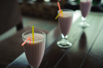 Three jars of pink berry milkshakes with straws on old wooden table