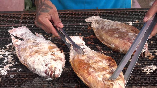 Thai street vendor sells grilled fish at street market in Thailand.