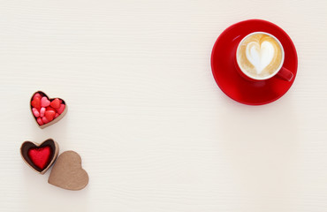 Valentine's day background. red cup of coffee with heart shape foam and chocolate. Top view image.