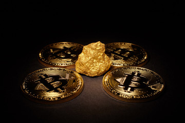 Closeup of big gold nugget and Gold Bitcoins Coins on black background