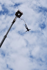 Bungee juming - seen from the ground silhouette of a young man rushing down from a high crane platform