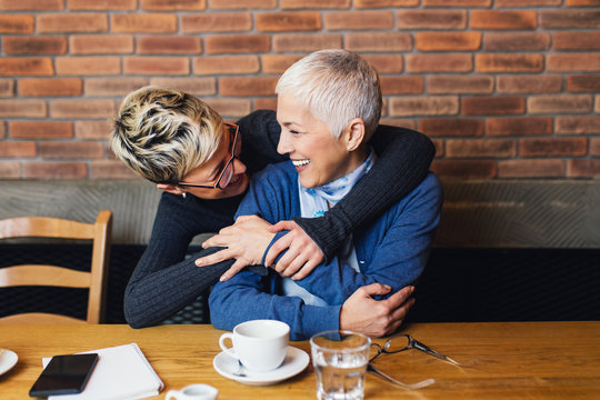 Senior Mother Sitting In Cafe Bar Or Restauant With Her Middle Age Daughter And Enjoying In Conversation.