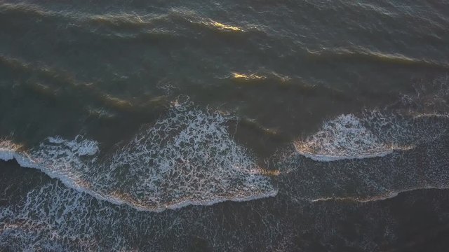Waves gentle break on the shore, warm summer evening. Aerial shot.