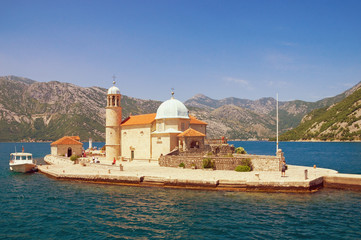 Fototapeta na wymiar View of Roman Catholic Church of Our Lady of the Rocks on a sunny summer day. Bay of Kotor, Montenegro. Free space for text
