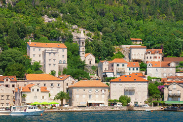 Fototapeta na wymiar View of old town of Perast with ancient stone palaces and Church of Our Lady of Rosary. Bay of Kotor, Montenegro, summer