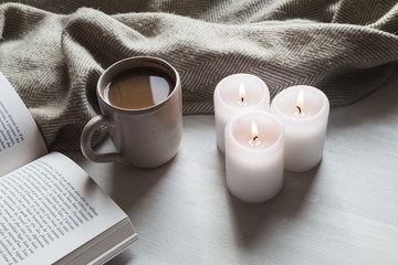 Fototapeta na wymiar Cozy hot chocolate and book with candles and blanket