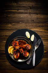 Roast chicken drumsticks on wooden background