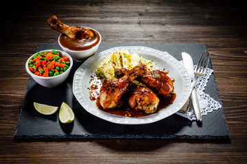 Grilled chicken legs with boiled potatoes on wooden background