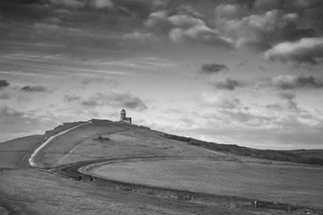 Stunning black and white landscape image of Belle Tout lighthouse on South Downs National Park during stormy sky