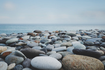 Fototapeta na wymiar pebble stone beach ocean and blue sky