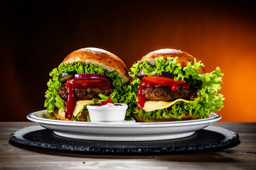 Two tasty burgers with cheese and ketchup served on white plate