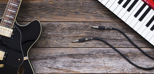 Electric guitar, keyboards and guitar cables on a wooden base
