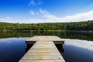 Fototapeta premium Empty footbridge over a tranquil lake in Mauricie national park, Canada