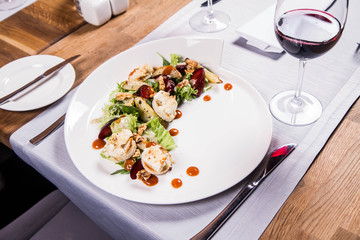 Starter: Mix salads, baked goat cheese, sea-buckthorn jam, caramelized pear with thyme, plum and roast nuts - served in a restaurant