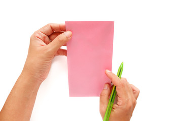 Obraz premium Hand holding a pen and being addressed on a pink envelope
