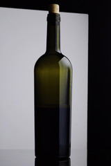 open Bottle of red Wine. Half a Bottle of Wine. A Bottle of Wine on a black and white background. Bottle with a cork isolated on a black and white background