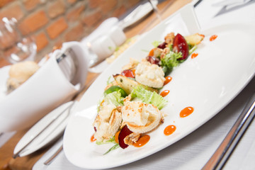 Starter: Mix salads, baked goat cheese, sea-buckthorn jam, caramelized pear with thyme, plum and roast nuts - served in a restaurant