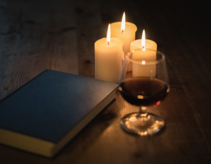 Buch, Glas und Kerzenschein