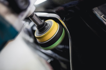 Car detailing - Hands with orbital polisher in auto repair shop. Selective focus.