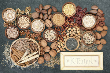 Dried high fibre health food concept with whole wheat pasta, grains, cereals, legumes, nuts and seeds with  rustic kitchen sign. Foods high in omega 3 fatty acids, antioxidants and vitamins.  