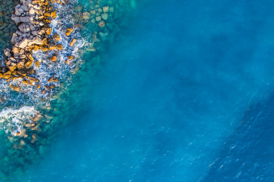 Aerial view on turquoise waves that beat against stones in Montenegro