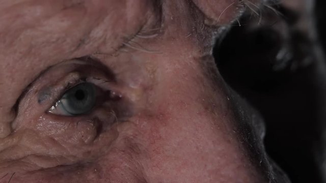 Very old 92 years man portrait. Grandfather sad and depressed. Aged, elderly, loneliness, senior. Macro eyes of man sitting alone. Slow motion.