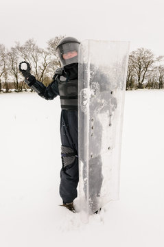 Police officer dressed in riot gear about to throw a snowball