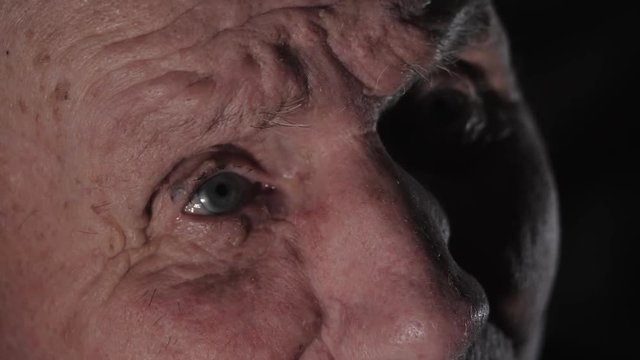 Very old 92 years man portrait. Grandfather sad and depressed. Aged, elderly, loneliness, senior. Macro eyes of man sitting alone. Slow motion.