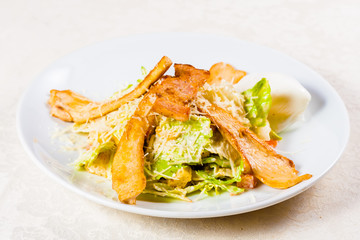 Caesar salad with chicken and parmesan cheese on white plate