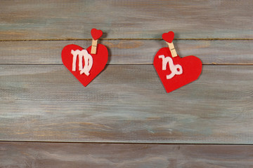 Virgo and Capricorn. signs of the zodiac and heart. wooden backg