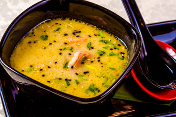 Asian seafood soup with spics and herbs in black bowl