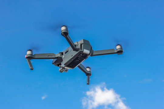 gray drone in the blue sky with clouds
