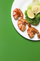 Ready cooked, fried tiger prawns. Delicious and healthy seafood dish. Three shrimps with lettuce and lemon slices.