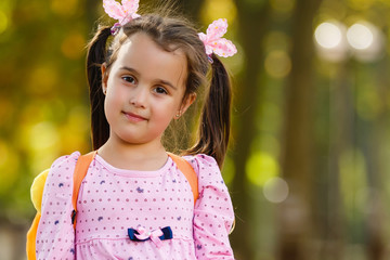 little schoolgirl with a backpack go to school