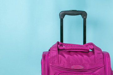 Traveling concept - pink suitcase in front of blue background