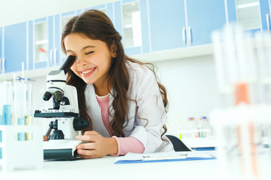 Little child with learning class in school laboratory using microscope
